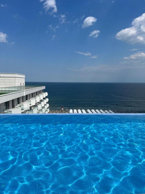 a swimming pool with chairs and the ocean in the background at Elite Summer Suite in Năvodari