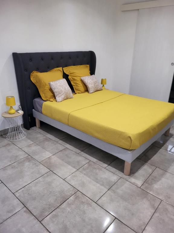 Bett mit gelber Bettwäsche und Kissen in einem Zimmer in der Unterkunft Résidence Ariane in Bourda