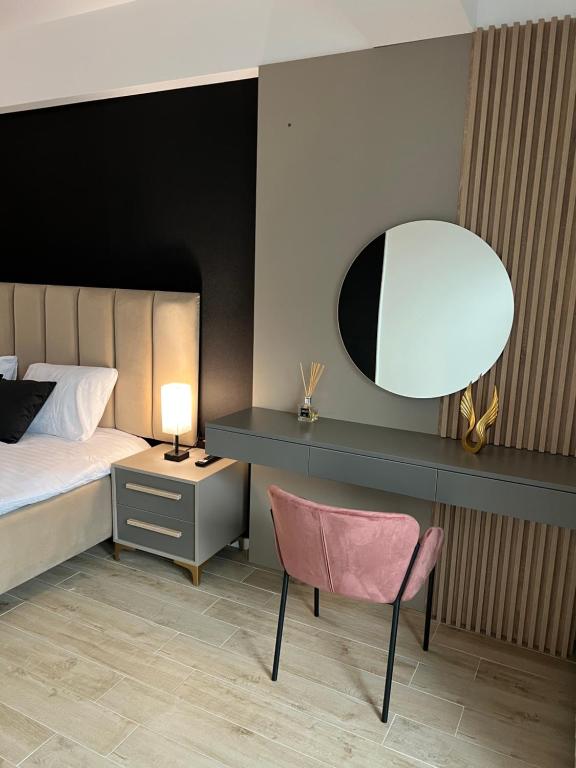a bedroom with a bed and a chair and a mirror at Elite Summer Suite in Năvodari