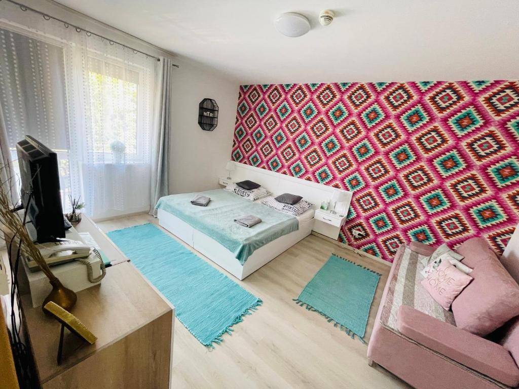 Habitación con cama, sofá y pared en Joy Apartman, en Zalakaros