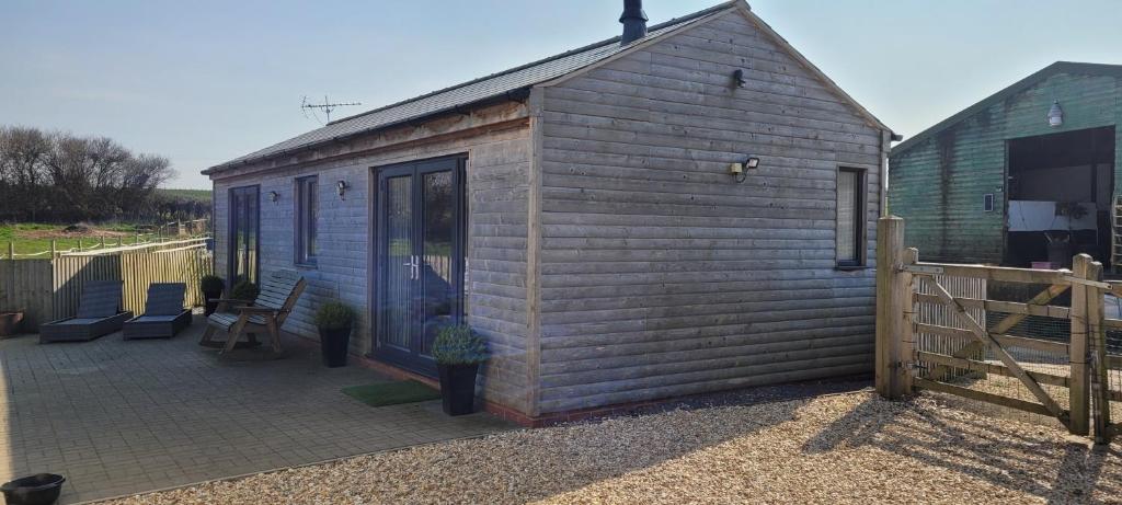 un pequeño cobertizo de madera con sillas y un patio en Adorable 1 bed log cabin with log burner, en Frome