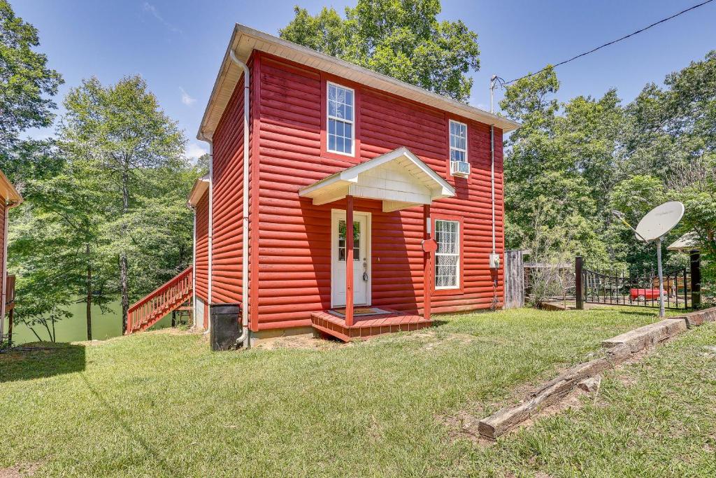 a red house with a white door in the grass at Secluded Alabama Retreat - Lewis Smith Lake Access 