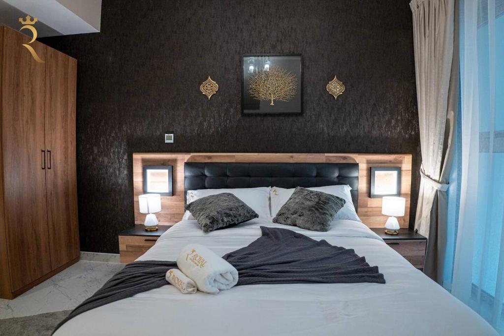 a bedroom with a large white bed with two pillows at Darkwood Haven - Luxe 2BR Duplex Stay in Oasis, Near Masdar City in Abu Dhabi