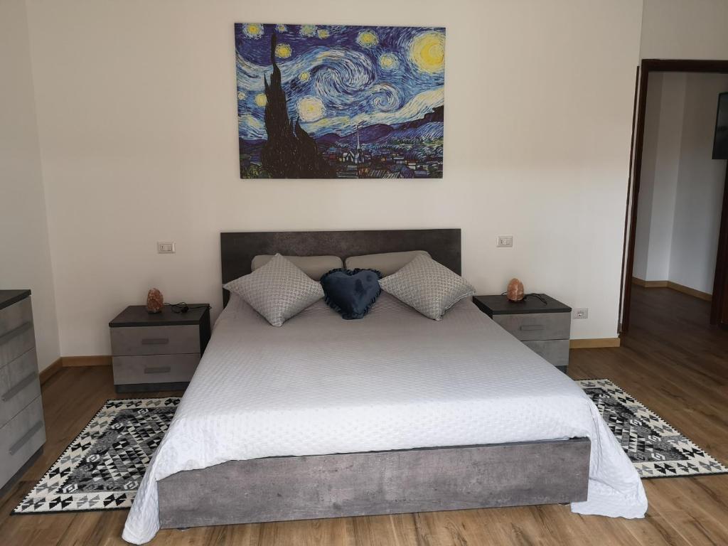 een slaapkamer met een groot bed met een schilderij aan de muur bij Ai Quattro Ulivi in Peschiera del Garda