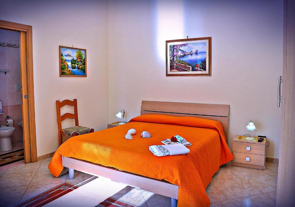 Un dormitorio con una cama naranja con dos animales de peluche. en B&B La Perla, en Castro di Lecce