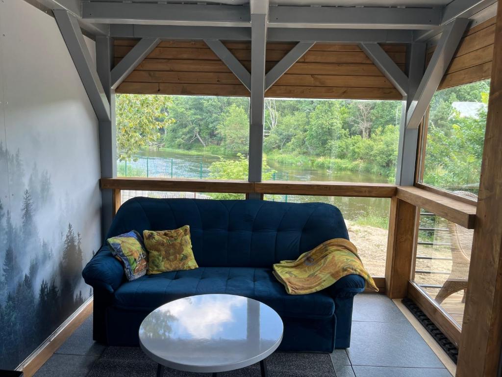salon z niebieską kanapą i szklanym stołem w obiekcie Domek Survivalowy w Spale w Spale
