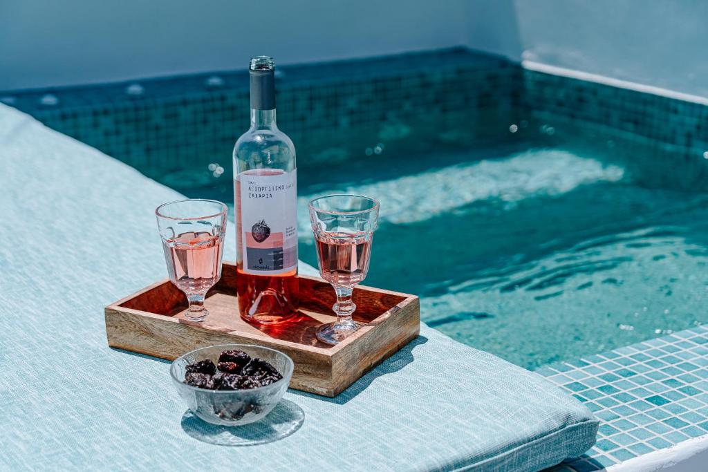 una bottiglia di vino e due bicchieri su un vassoio accanto alla piscina di Moon Cactus Traditional Cave Suite with Jacuzzi a Mesariá