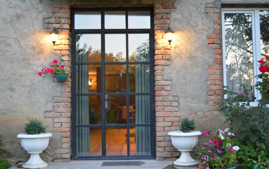 a door to a house with two white vases at Velio Guest House in Velistsʼikhe