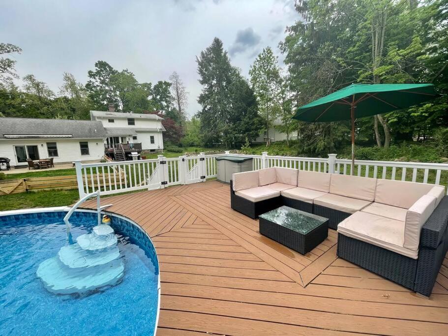 - une terrasse avec un canapé et un parasol à côté de la piscine dans l'établissement Pool, heated floors, king bed. Perfect getaway., à Warwick