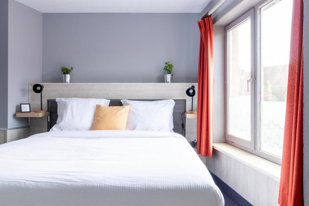 1 dormitorio con cama blanca y ventana en Entree en Bruges