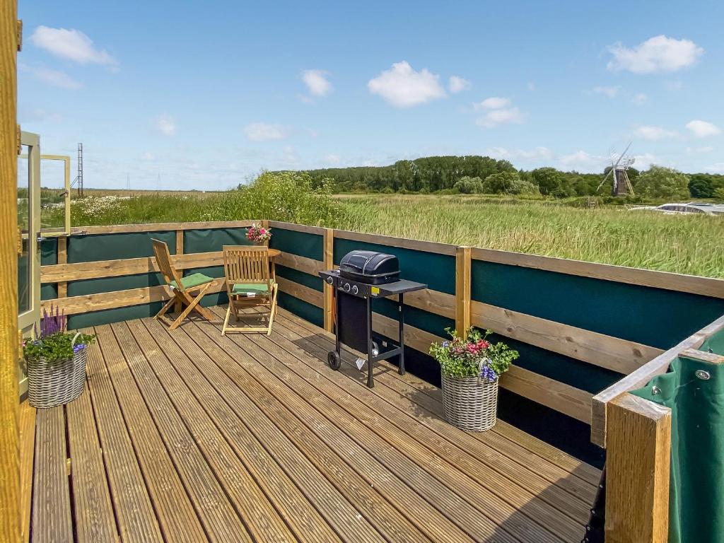 a deck with a grill and a table and chairs at Reed View in Fritton