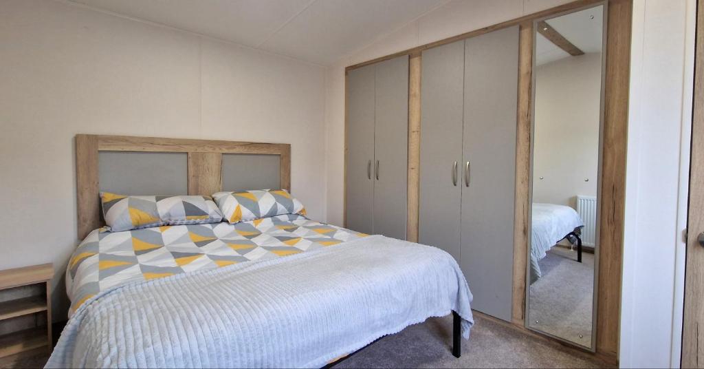 1 dormitorio con 1 cama grande y espejo en Cwtch, White Horse, Seal Bay Resort, en Selsey