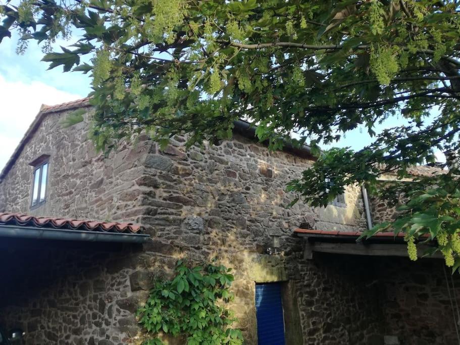 un edificio in pietra con finestra e albero di Casa rural de piedra en una aldea tranquila de Zas 