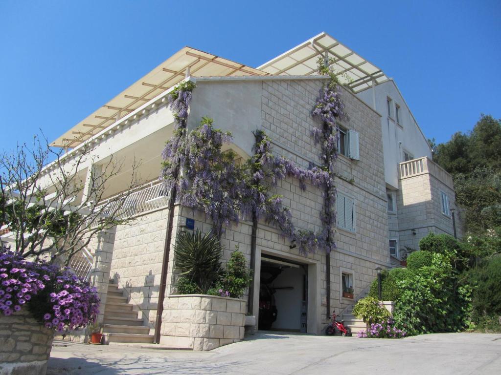 un bâtiment avec des fleurs violettes sur son côté dans l'établissement Villa Hela, à Lumbarda