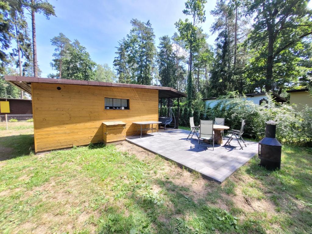 a backyard with a wooden cabin with a table and chairs at Domek Seleny w Dolinie Symsarny in Lidzbark Warmiński