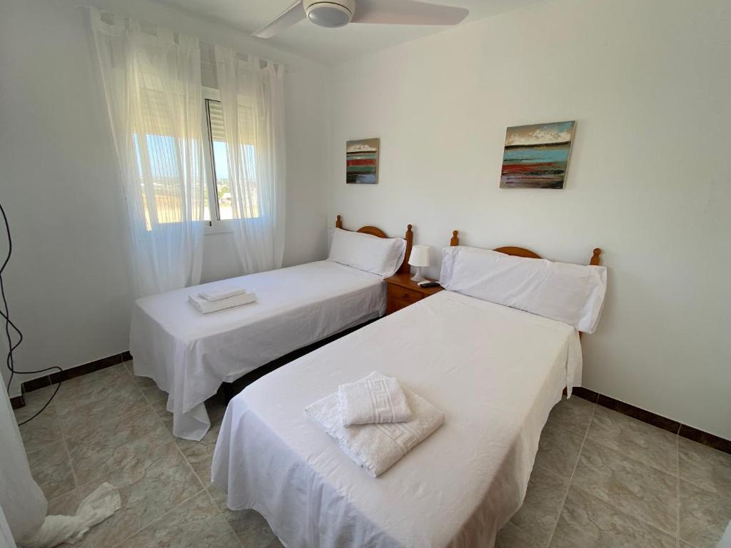 two beds in a room with white walls at Alojamiento Rural Al´Mare in Conil de la Frontera