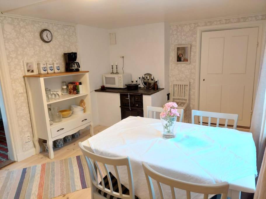 une cuisine avec une table et un vase de fleurs. dans l'établissement Trevligt eget hus med kakelugn i lantlig miljö, à Vikingstad