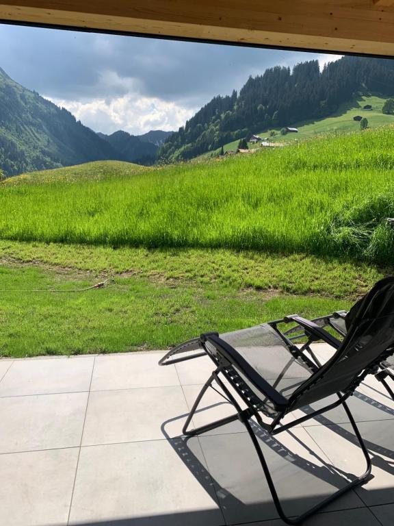 a chair on a porch with a view of a field at Kracha Alpinlodge in Mittelberg