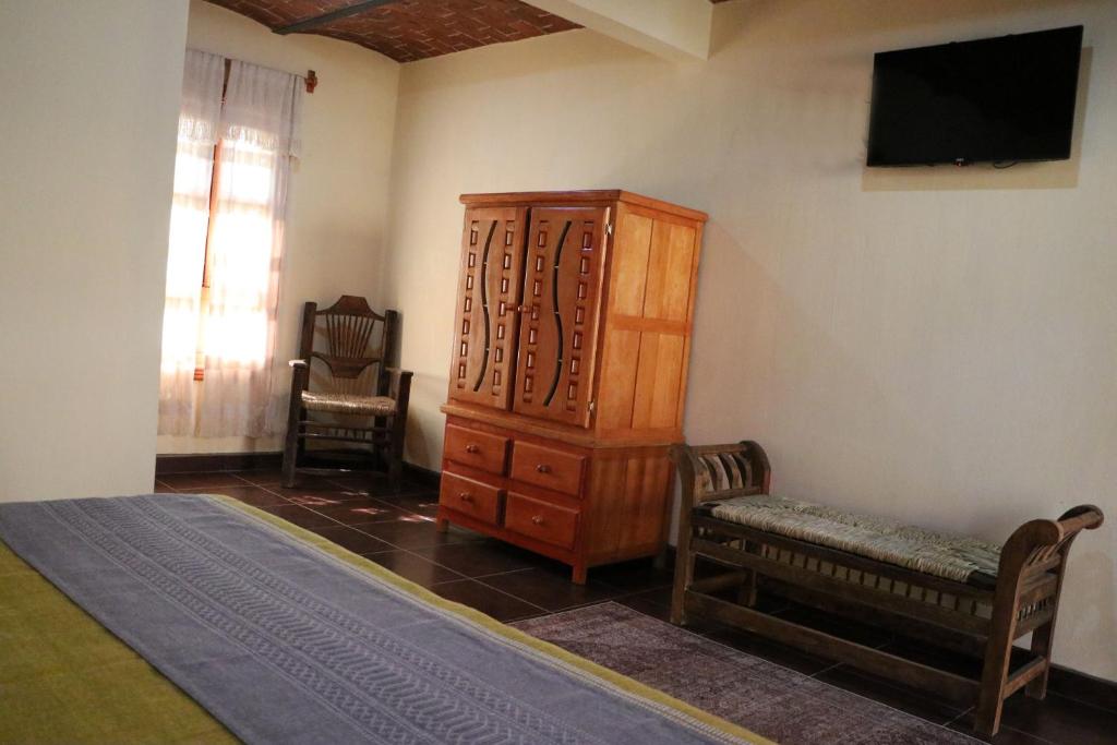 a bedroom with a bed and a cabinet and a chair at Hotel Castillo Santa Cecilia in Tapalpa