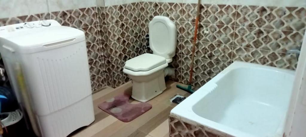 een badkamer met een wit toilet en een wastafel bij العجمي البيطاش بيانكى in Alexandrië