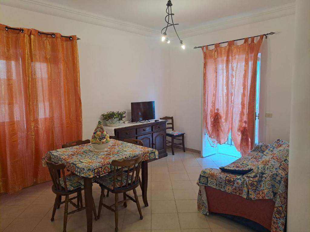 ein Wohnzimmer mit einem Tisch, Stühlen und einem TV in der Unterkunft DreamHouse Ischia-Lacco Ameno in pieno centro a soli 70 metri dal mare! in Ischia