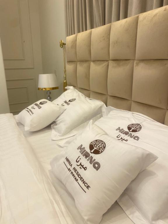 two white pillows on a bed with the words happy new year at مساكن ميرنا in Taif