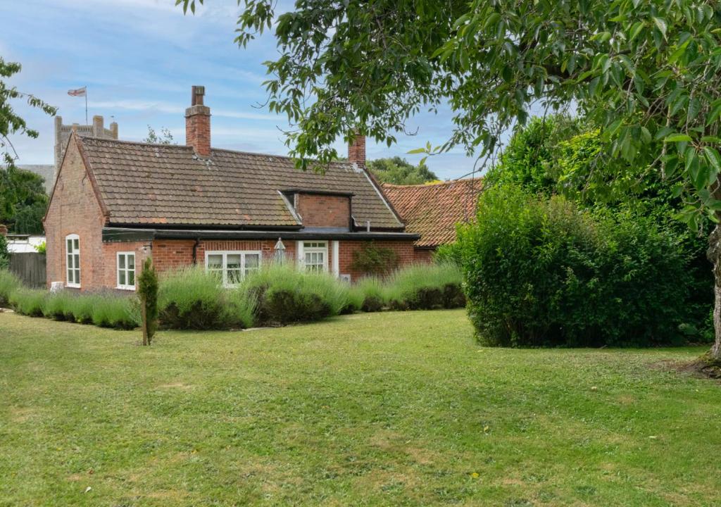 a red brick house with a grass yard at Old Rectory Cottage in Orford