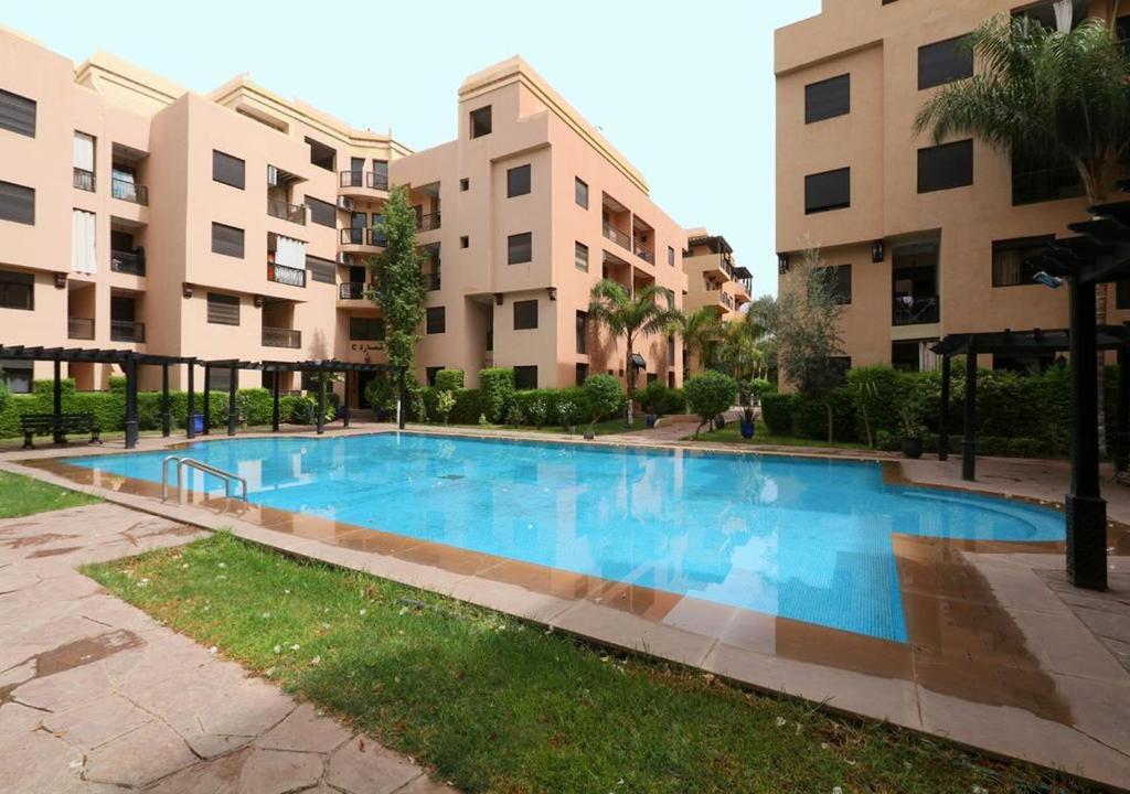 ein großer blauer Pool vor einigen Gebäuden in der Unterkunft Appartement Jawhara in Marrakesch