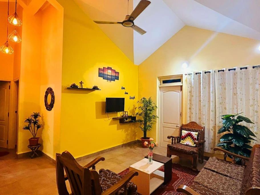 a living room with yellow walls and a ceiling at Reev's Homestay: Luxury 2 Bedroom apartment in Arossim-Cansaulim
