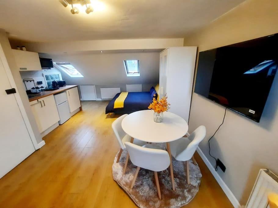 una habitación con mesa y sillas y un dormitorio en Alross studio flat / private bathroom, en Londres
