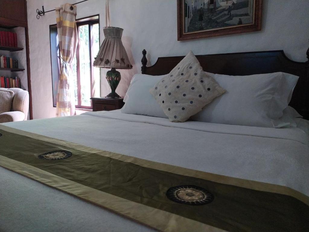 een slaapkamer met een groot bed met witte lakens en kussens bij Posadas Le Petit Inn in Caracas