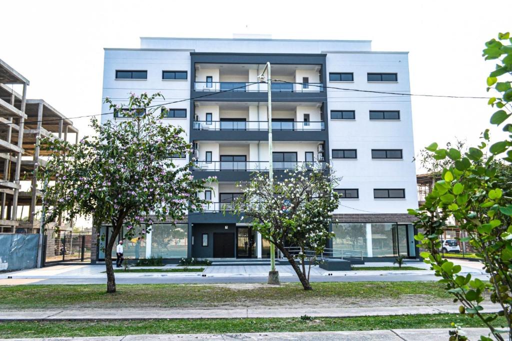 a white building with trees in front of it at Dpto Piacentini in Resistencia