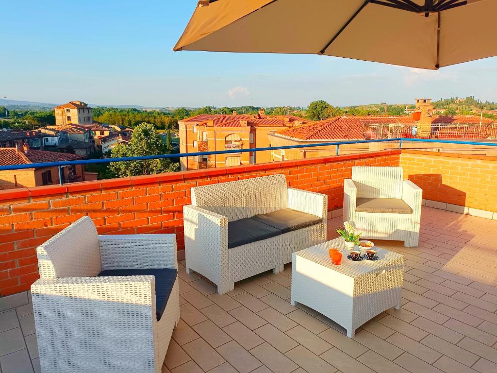 eine Terrasse mit Stühlen, einem Tisch und einem Sonnenschirm in der Unterkunft [Siena] Appartamento con splendido terrazzo in Presciano