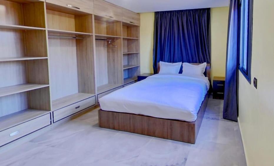 a bedroom with a large white bed and shelves at KHALIJ HOSPITALITE in Dakhla