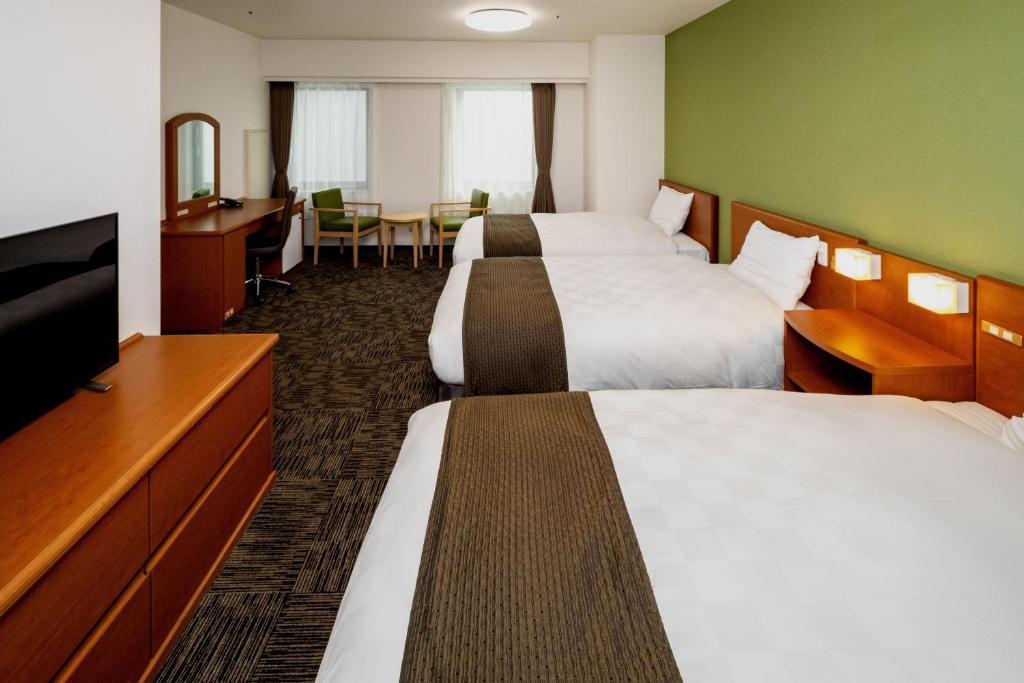 a hotel room with two beds and a flat screen tv at Kumamoto Tokyu REI Hotel in Kumamoto