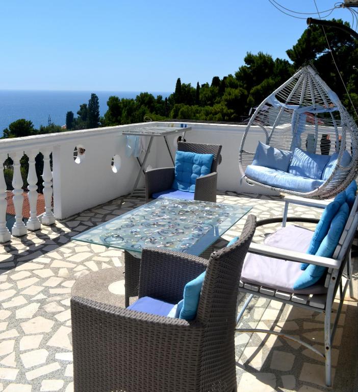 a patio with chairs and a glass table and swings at Holiday house Ogi in Bar