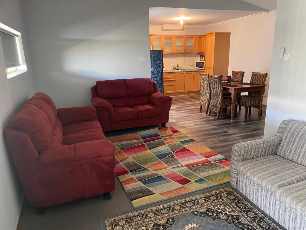 a living room with two chairs and a red couch at Quaint Flat, Outside Dog Friendly, near hospital in Geraldton