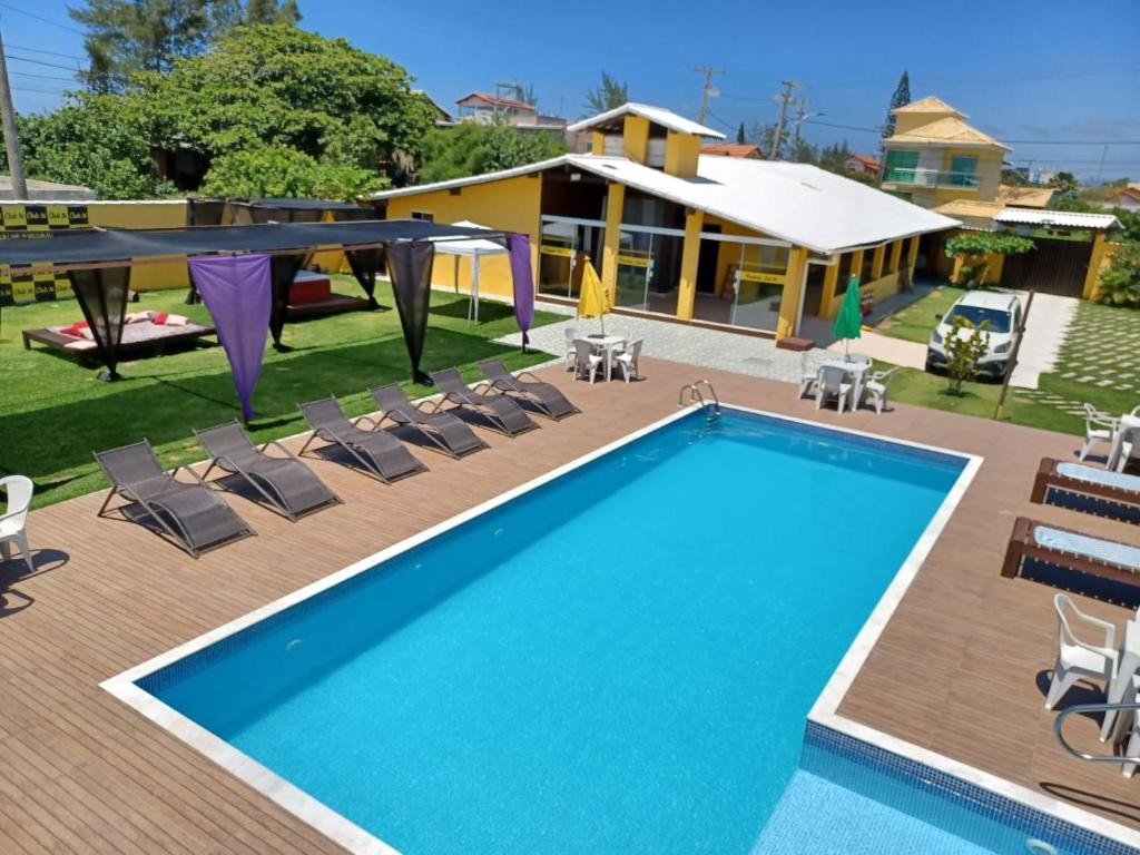a pool with chairs and a table and a house at Pousada X in Saquarema