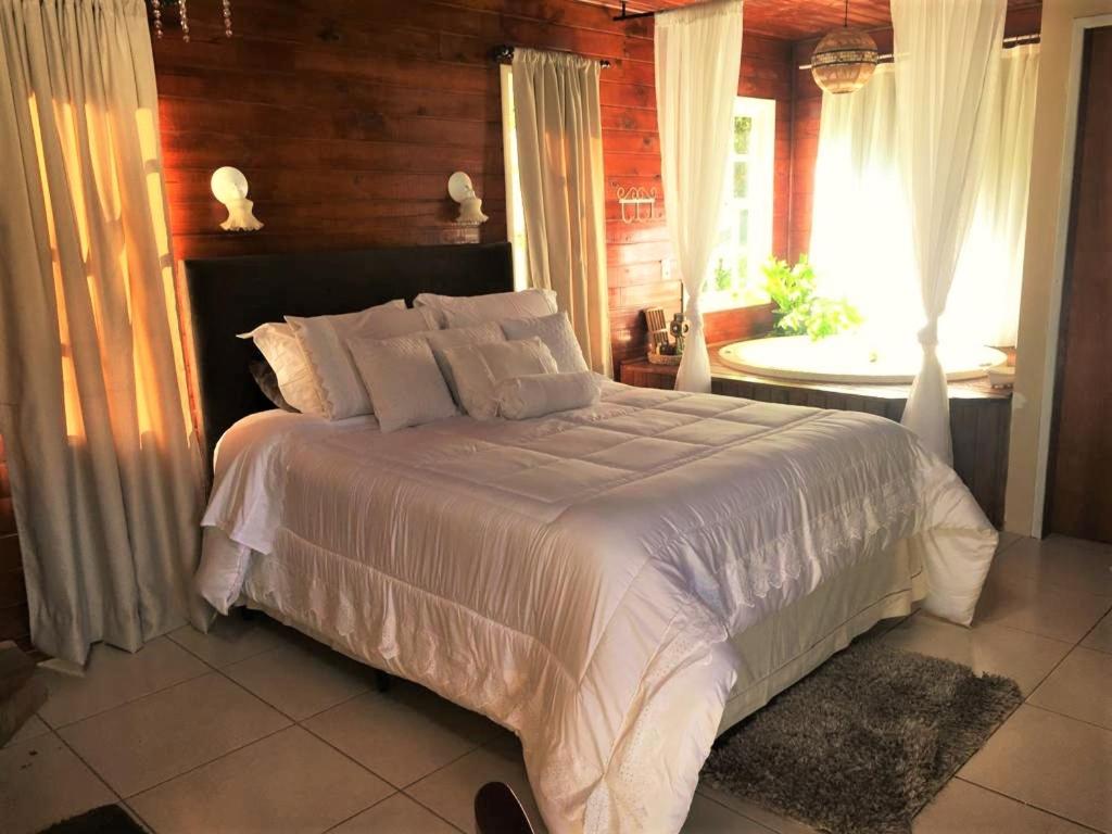 um quarto com uma grande cama branca e uma janela em Cabana dos Sonhos na Serra SC em Rancho Queimado