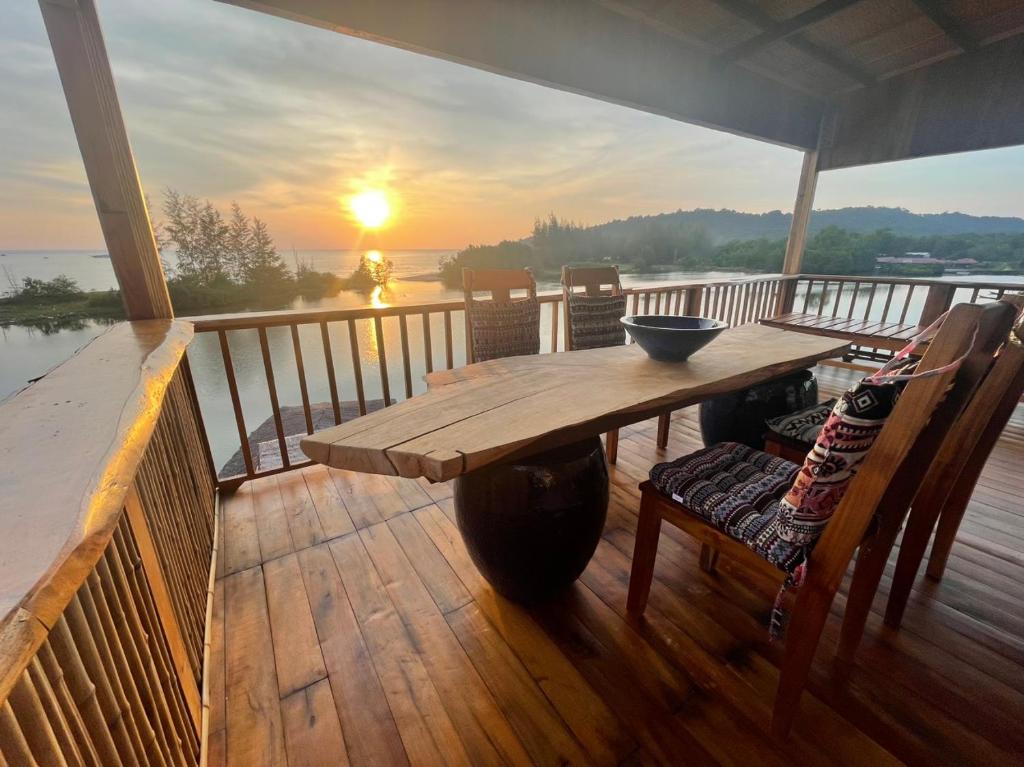 a wooden table and chairs on a deck with the sunset at Eco Lagoon in Phu Quoc