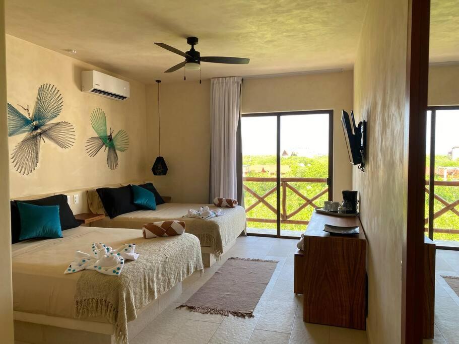 1 dormitorio con 2 camas y ventilador de techo en sunsteps dragonfly room, en Isla Holbox