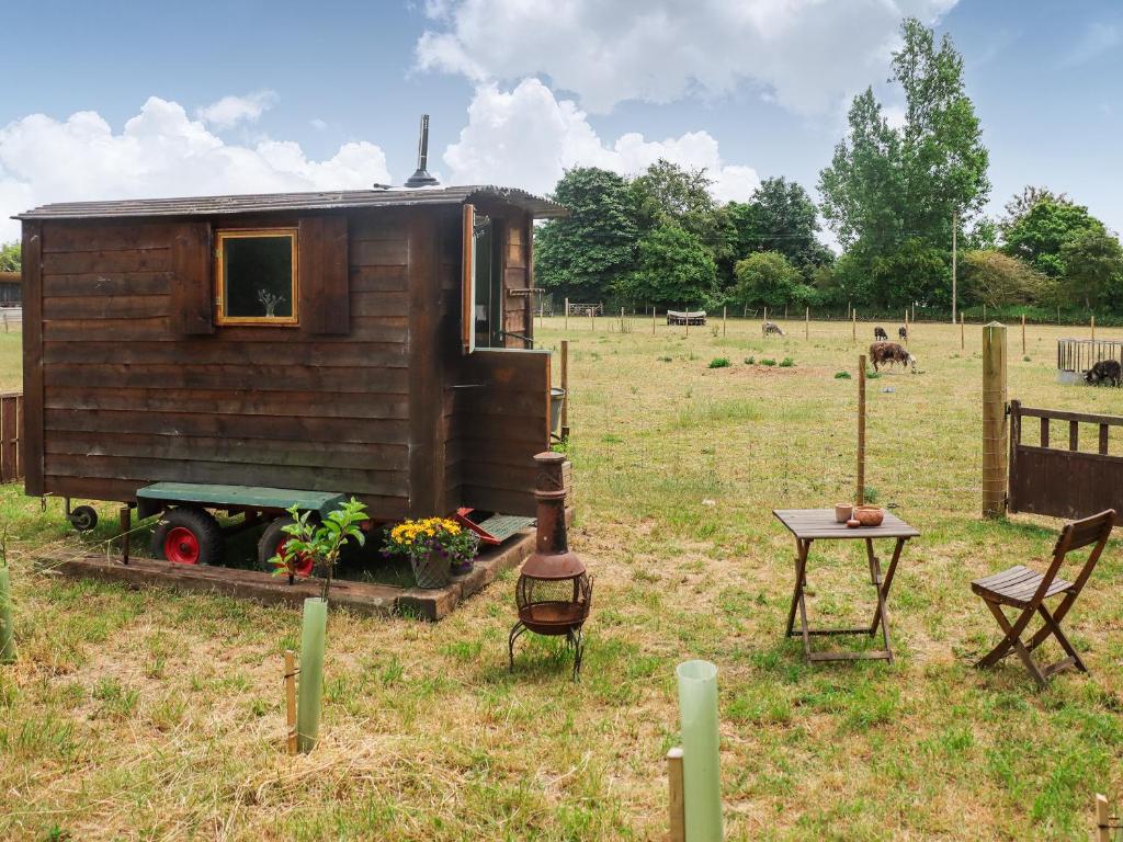 a tiny house in a field with a table and chairs at Falgate Shepherds Hut in Caston