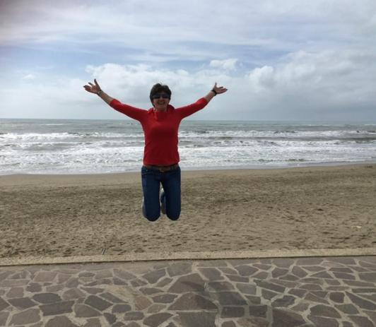 a woman jumping in the air on the beach at Attico al mare Zoomarine a 40 minuti da Roma in Torvaianica