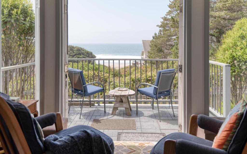 a room with a balcony with chairs and a view of the ocean at Breeze Cottage in Depoe Bay