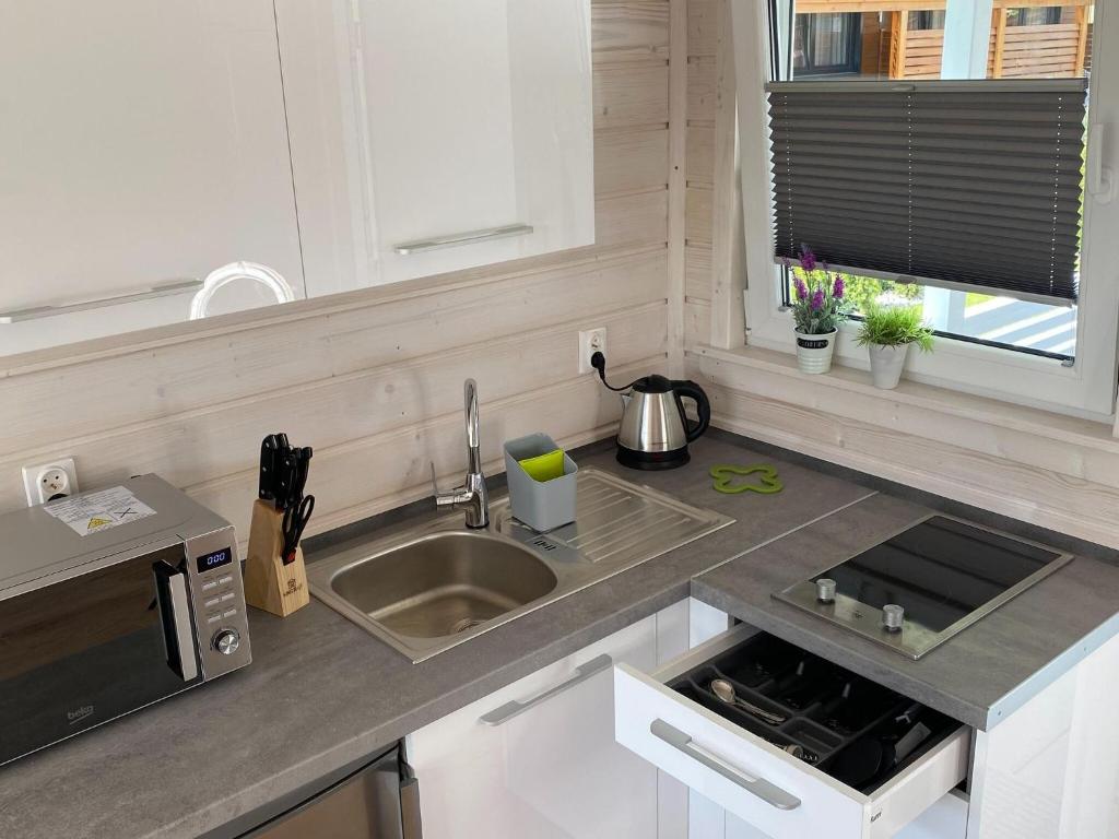 a kitchen with a sink and a microwave at Comfortable holiday houses D bki in Dąbki