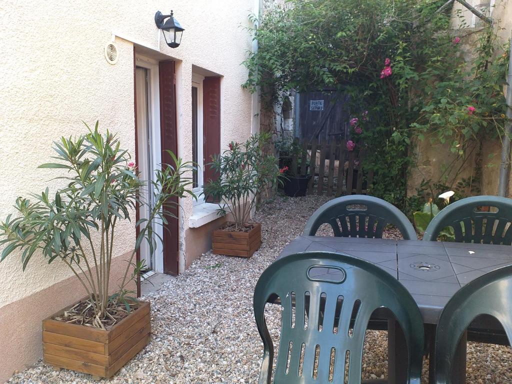 una mesa y sillas en un jardín con plantas en Maison Berrichonne avec cour et jardin intime, en Saint-Marcel