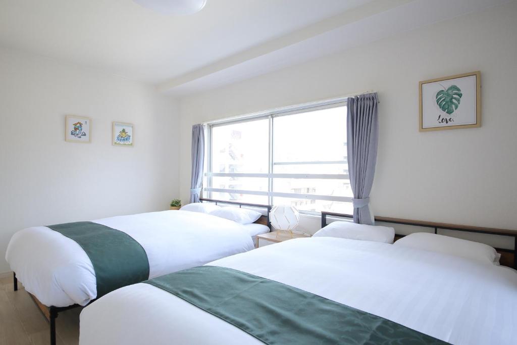 Duas camas num quarto com uma janela em 大阪ハウス701 Near Namba and Kuromon Market and Den Den Town & Direct to KIX em Osaka