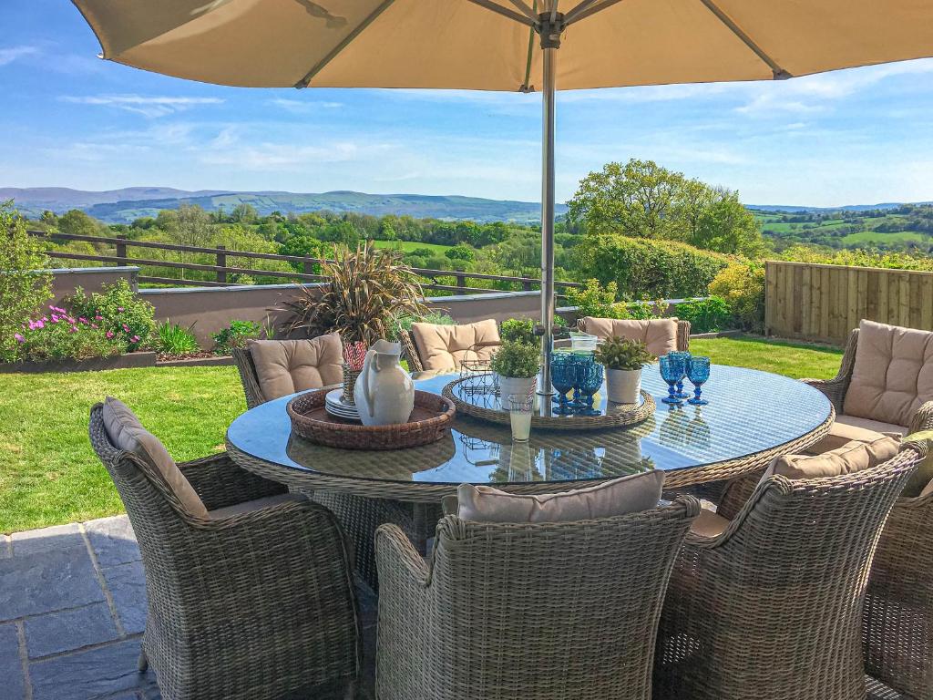 a table with chairs and an umbrella on a patio at Maes Y Bryn Farmhouse in Llanwrda
