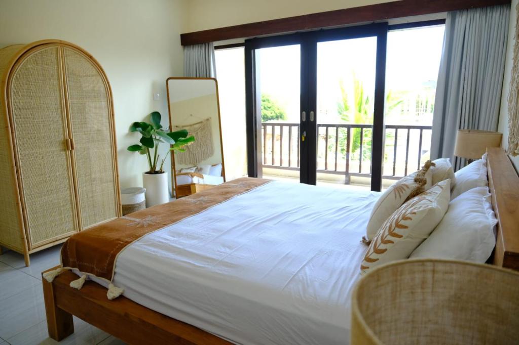 a bedroom with a large bed and a balcony at Kala Surf Camp in Uluwatu