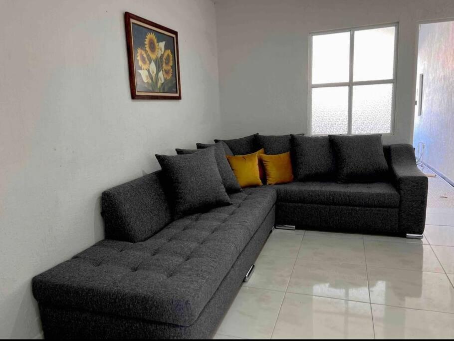 - un canapé noir dans le salon doté d'une fenêtre dans l'établissement 1 casa cochera 2 recamaras centrica, à Torreón